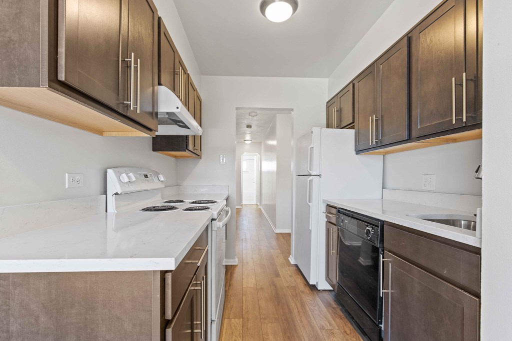an empty kitchen with wood flooring and white counter tops