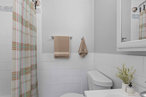 a white bathroom with a striped shower curtain and a toilet and a sink