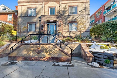 A brick building with a black metal staircase leading to the front door.