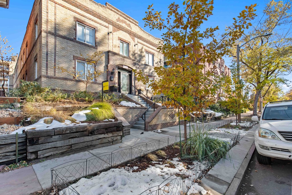 A building with a brown brick facade and a white car parked in front.