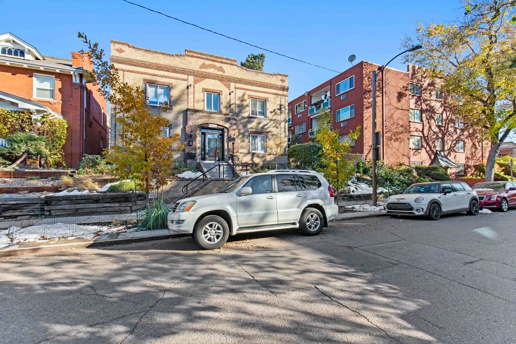 A silver SUV is parked on a street with other cars and buildings in the background.