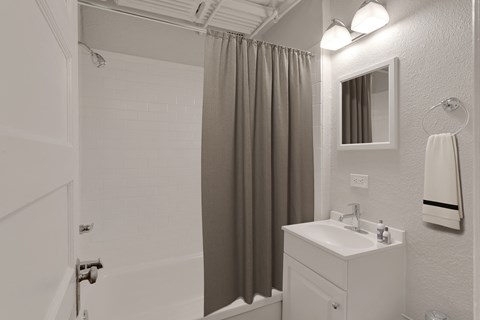 A white bathroom with a sink, mirror, and shower.