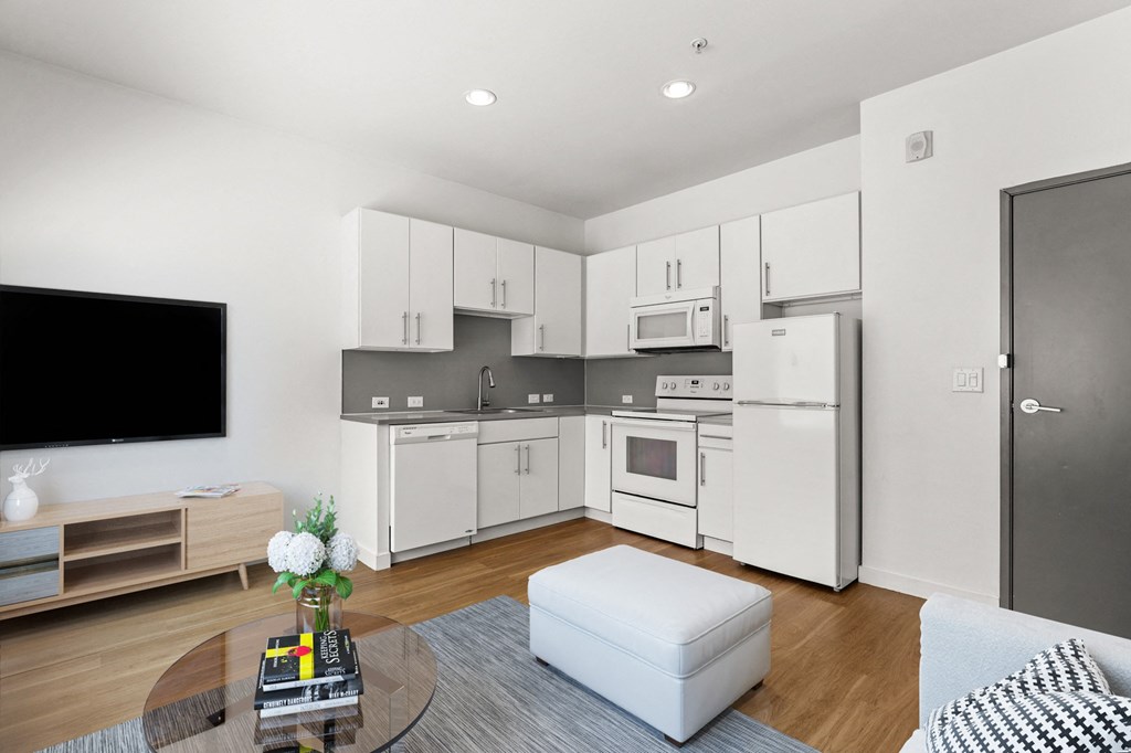 a kitchen and living room with white cabinets and a white coffee table
