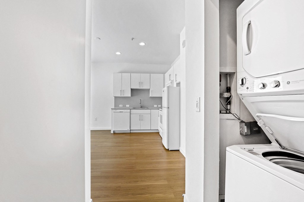 a kitchen with white cabinetry and a washer and dryer
