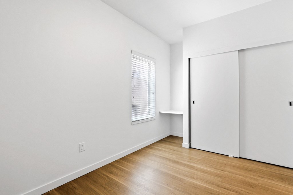 a bedroom with white walls and hardwood floors