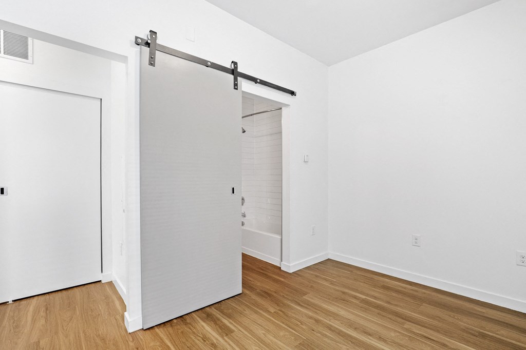 a bedroom with a white door and hardwood floors