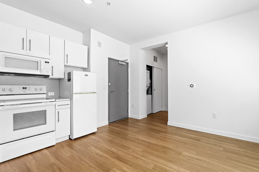 a kitchen and living room with white walls and wood floors