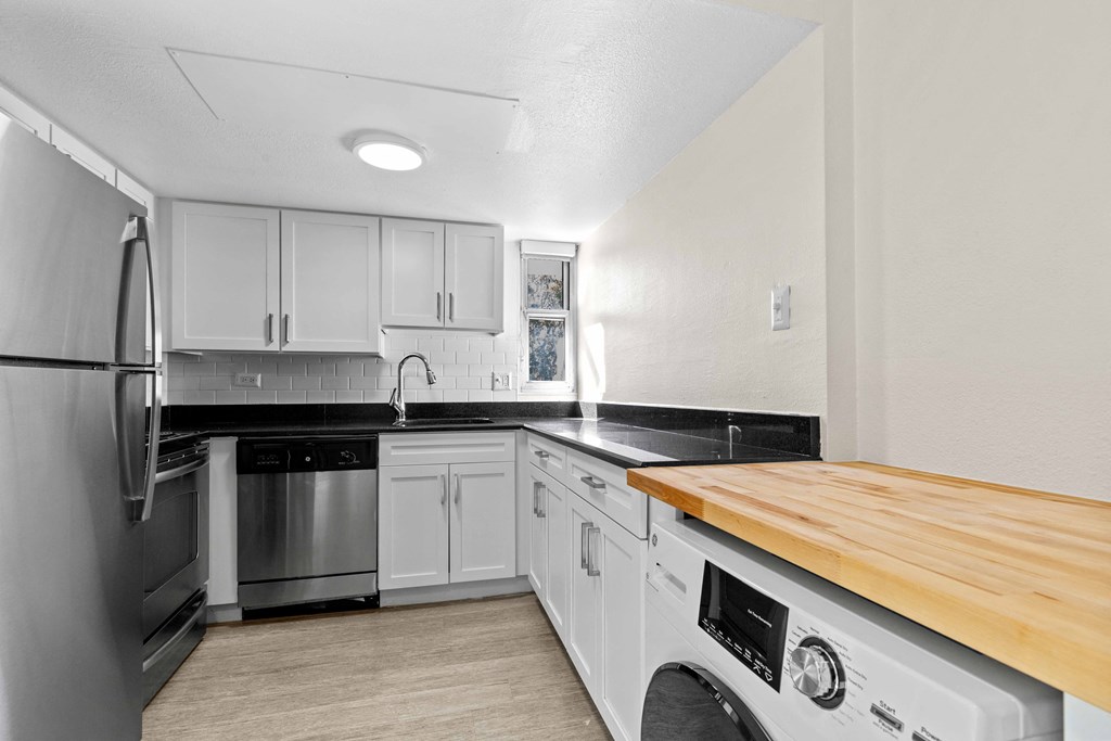 a kitchen with white cabinets and stainless steel appliances and a wood counter top