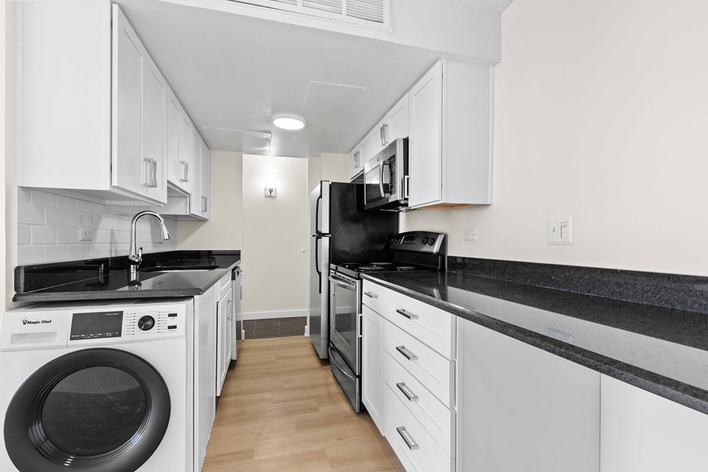 a kitchen with white cabinets and black counter tops and a washing machine