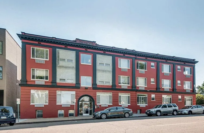 A red building with a black car parked in front.