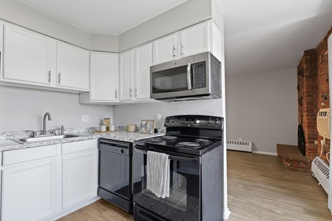 a kitchen with white cabinets and black appliances