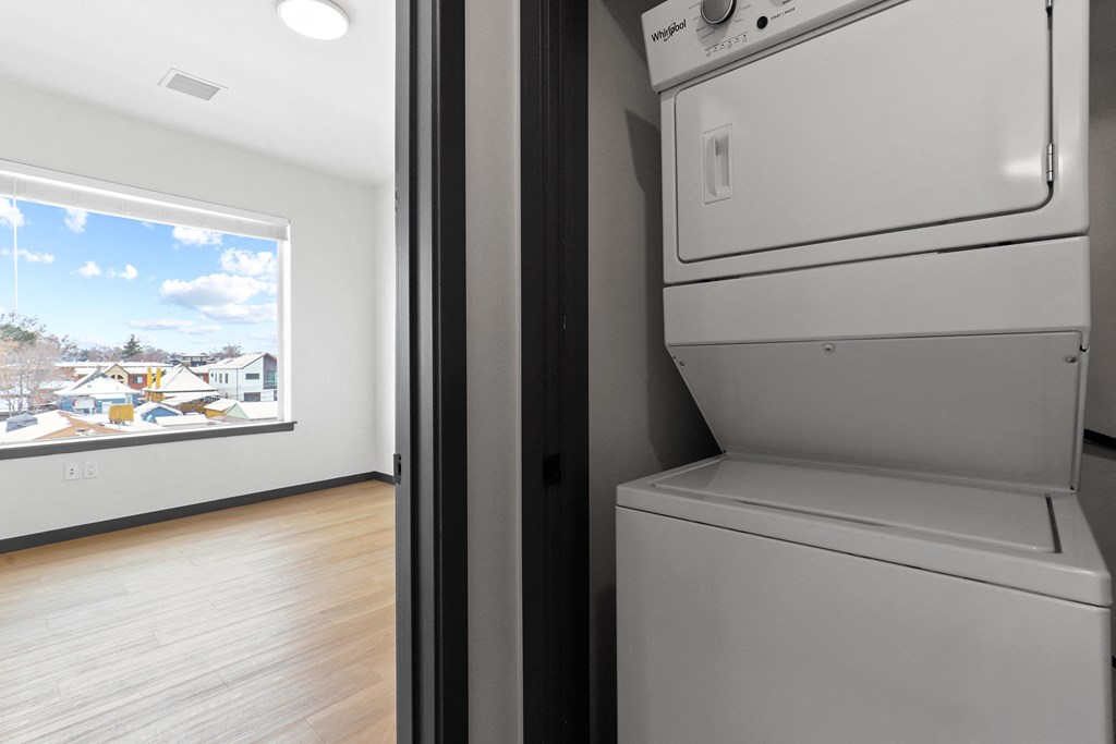 the living room has a washer and dryer and a window overlooking the city