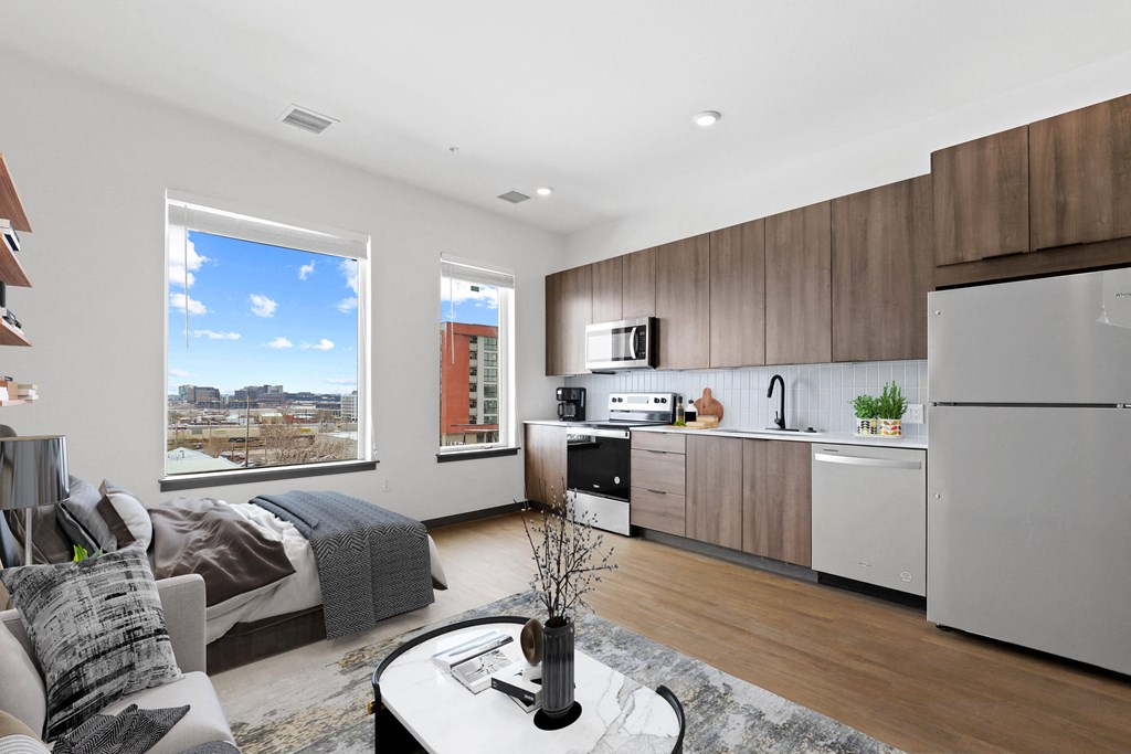 an open living room with a kitchen and a bed