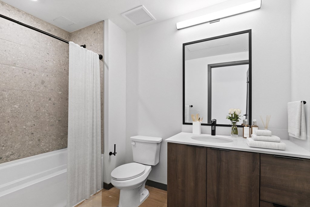 a bathroom with a toilet sink and shower and a mirror