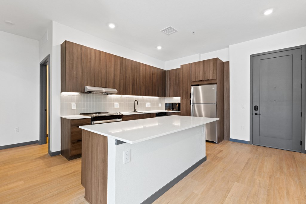 a large white kitchen with wooden cabinets and a stainless steel refrigerator