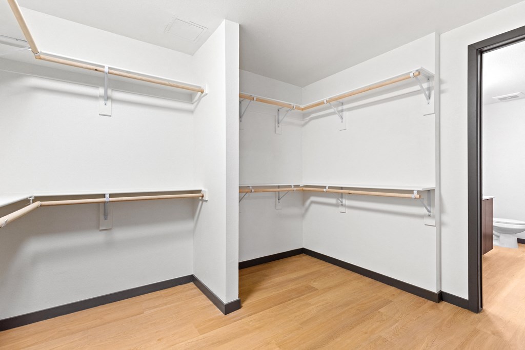 an empty room with white walls and wooden floors and a mirrored closet