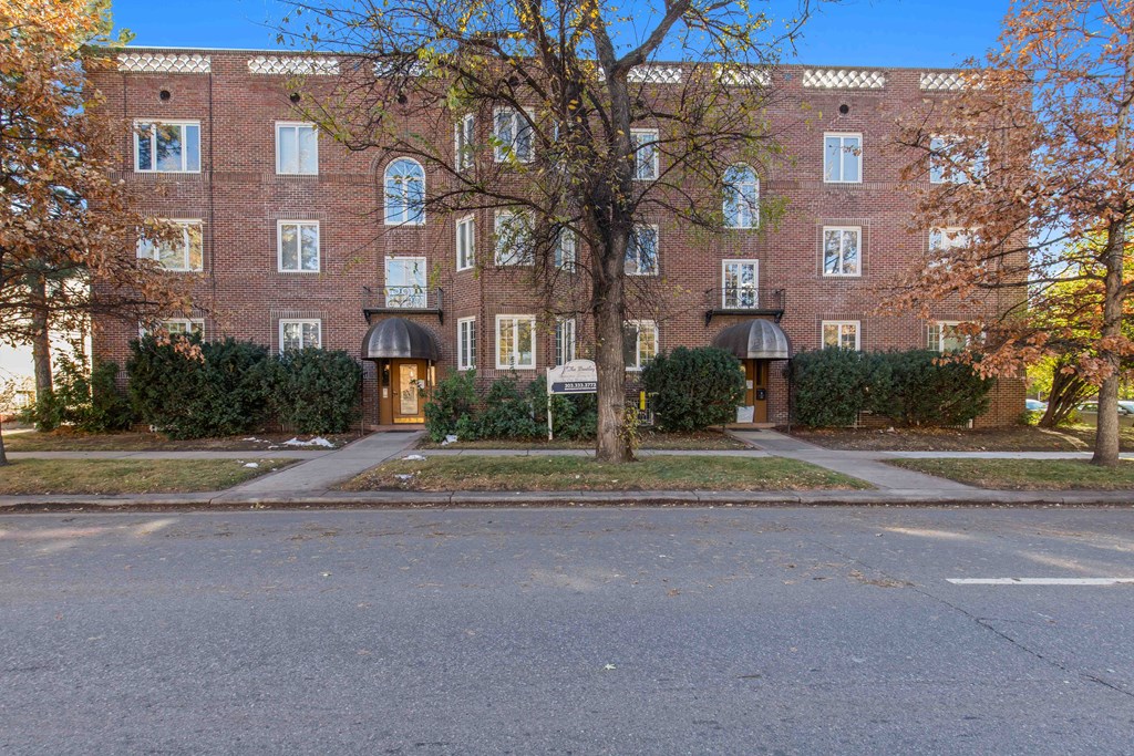 A red brick building with a tree in front of it.