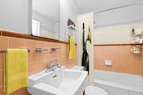 A bathroom with a white sink and a yellow towel.