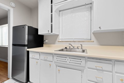 A kitchen with white cabinets and a black refrigerator.