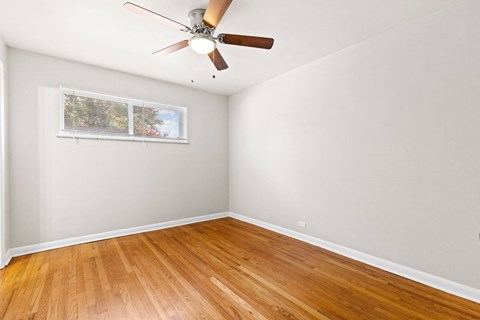 A room with a ceiling fan and a window with blinds.