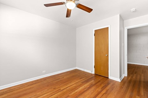 A room with a ceiling fan and wooden floors.