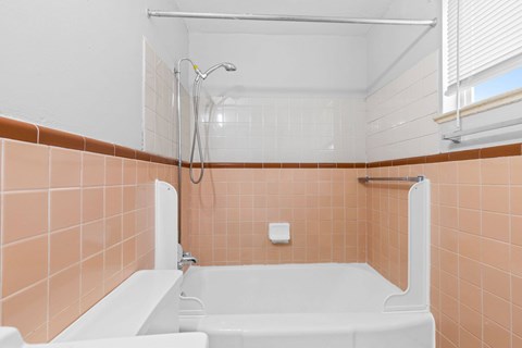 A white bathtub with a shower head and a shower curtain rod.