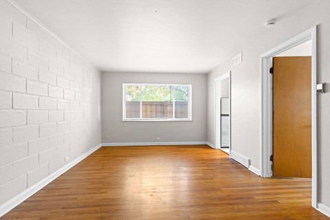A room with a wooden floor and a white brick wall.