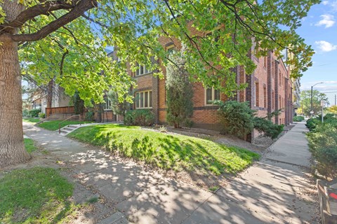 a sidewalk in front of a brick building with green grass