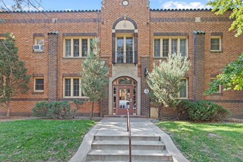 the front of a brick building with a red door