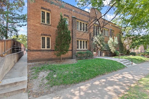the exterior of a brick building with a sidewalk and grass