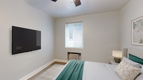 A bedroom with a bed, a television, and a window.