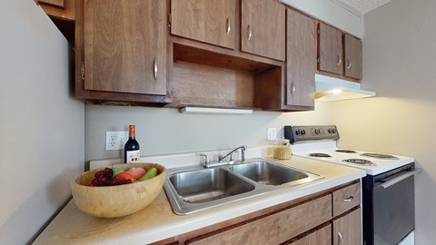 A kitchen with wooden cabinets and a bowl of fruit on the counter.
