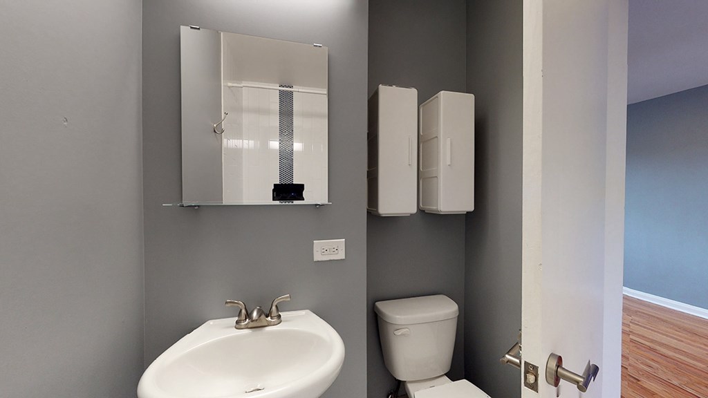 A bathroom with a sink, toilet and mirror.