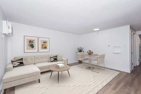 A living room with a white couch, a coffee table, and a small dining table with chairs.
