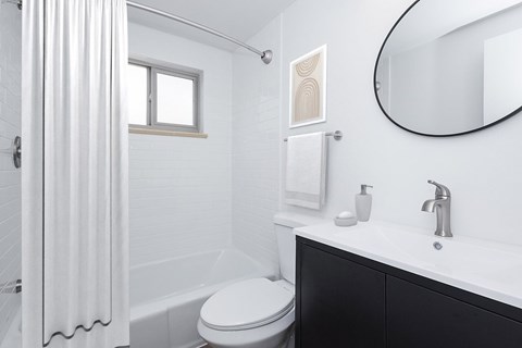A white bathroom with a toilet, sink, and mirror.