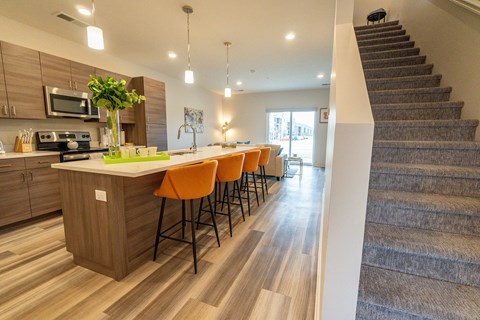 a kitchen with a bar and stairs in a house