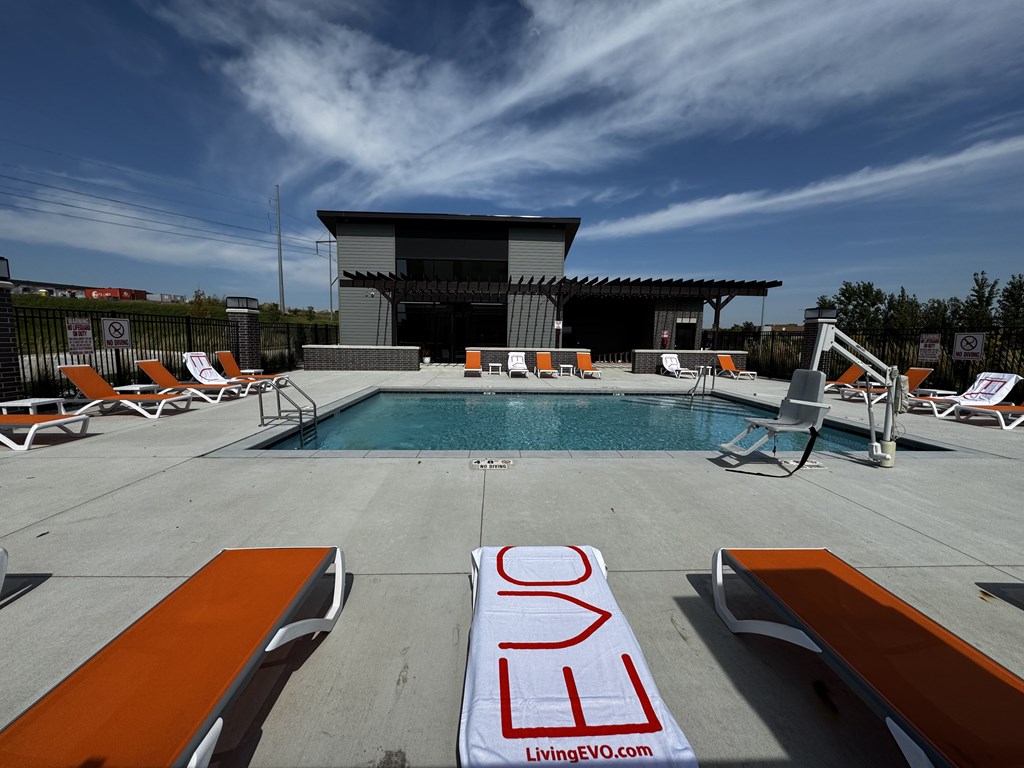 A pool area with loungers and a sign that reads "LivingEVO.com".