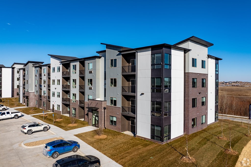 A row of modern apartment buildings with cars parked in front.