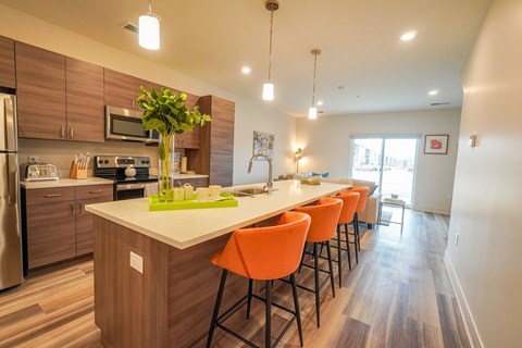 a kitchen with a long island with orange chairs