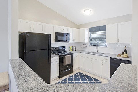 a renovated kitchen with black appliances and white cabinets