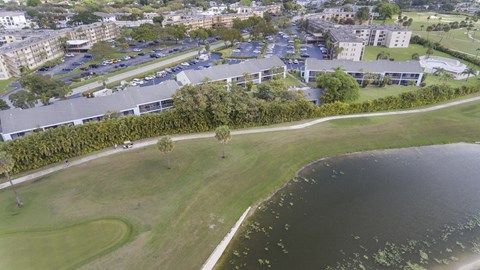 A large building sits next to a body of water with a parking lot in front.