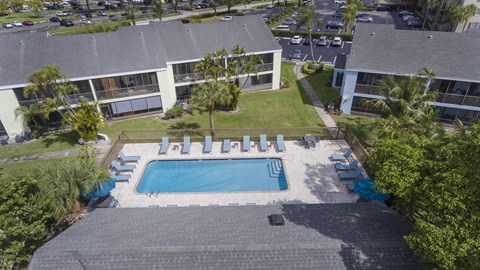 An aerial view of a swimming pool surrounded by buildings and palm trees.