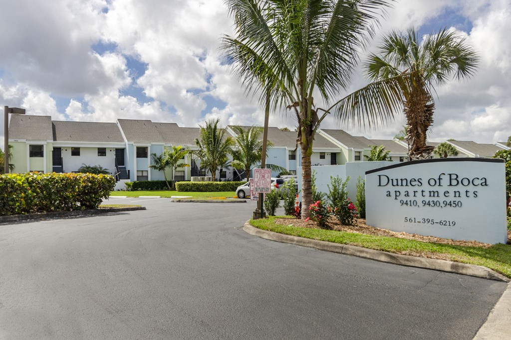 Dunes of Boca Apartments is a residential complex with a palm tree in front.