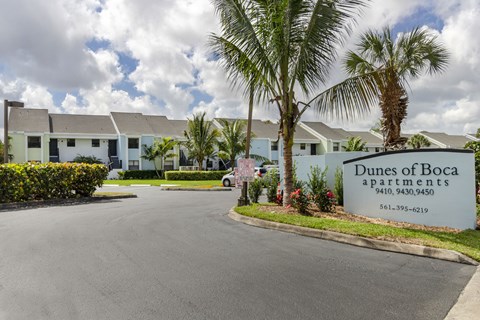 Dunes of Boca Apartments is a residential complex with a palm tree in front.