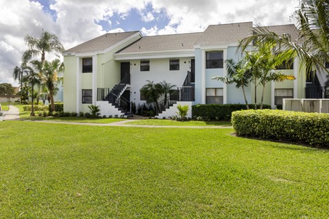 A white two-story house with a black railing on the balcony.