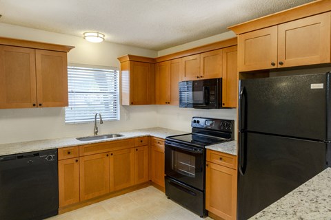 A kitchen with black appliances and wooden cabinets.