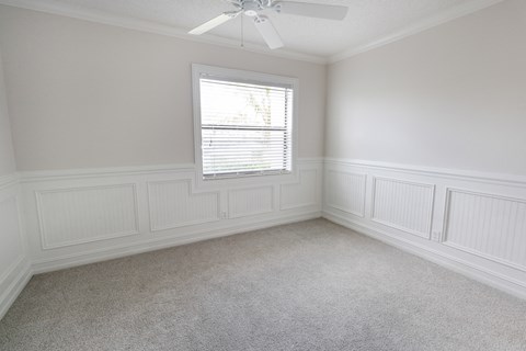 A room with a window and a ceiling fan.