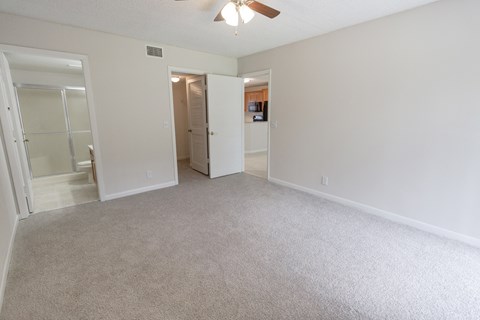 A room with a carpeted floor and a ceiling fan.