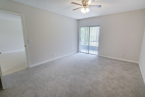 A room with a ceiling fan and a window with blinds.