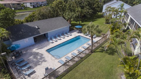 A pool surrounded by a fence and chairs.